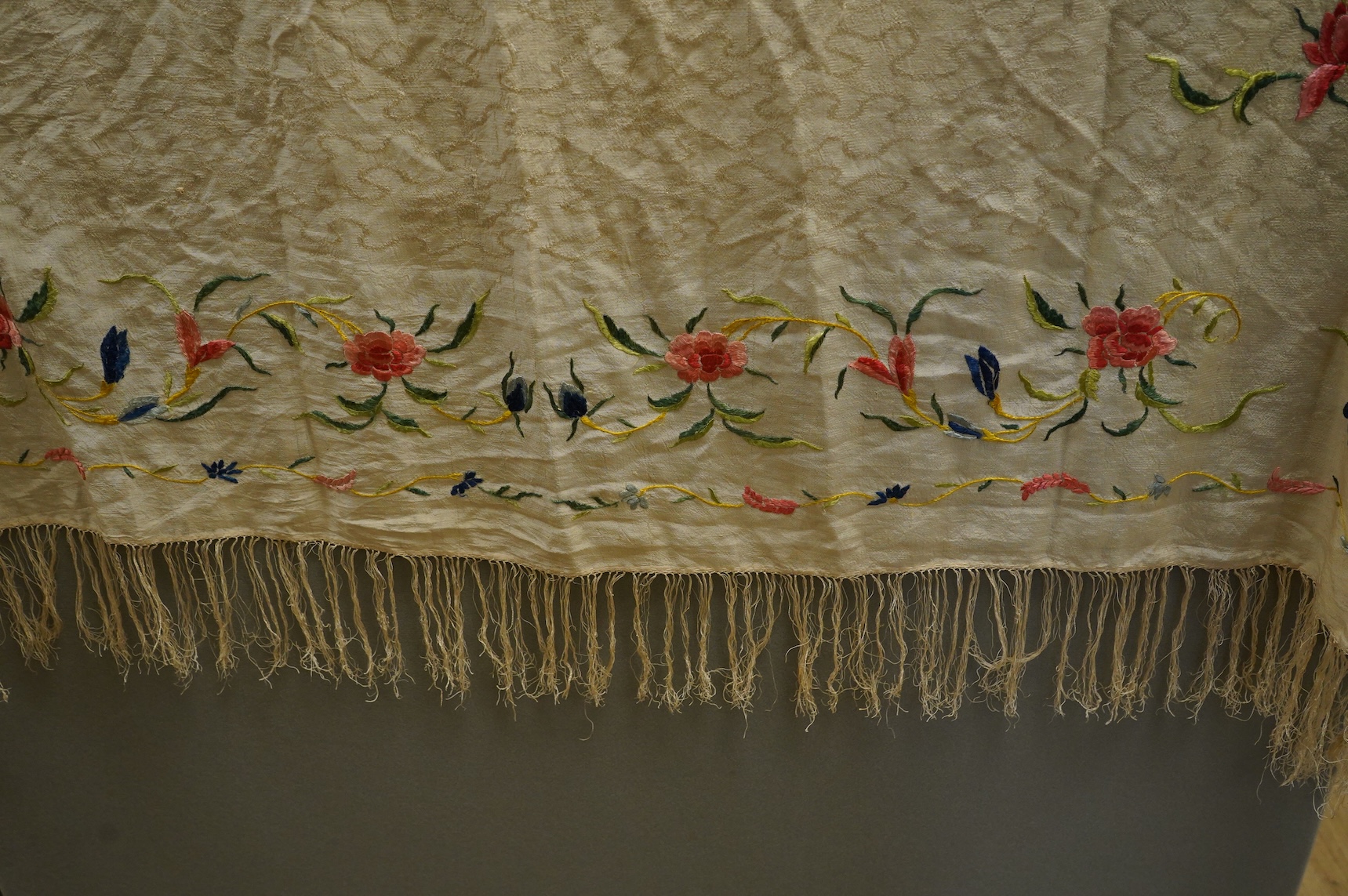 An early Chinese 20th century cream silk damask shawl with a polychrome floral silk embroidered border and a silk fringe, 150cm x 150cm, together with a smaller shawl/scarf, the corner cream on cream embroidered and edgi